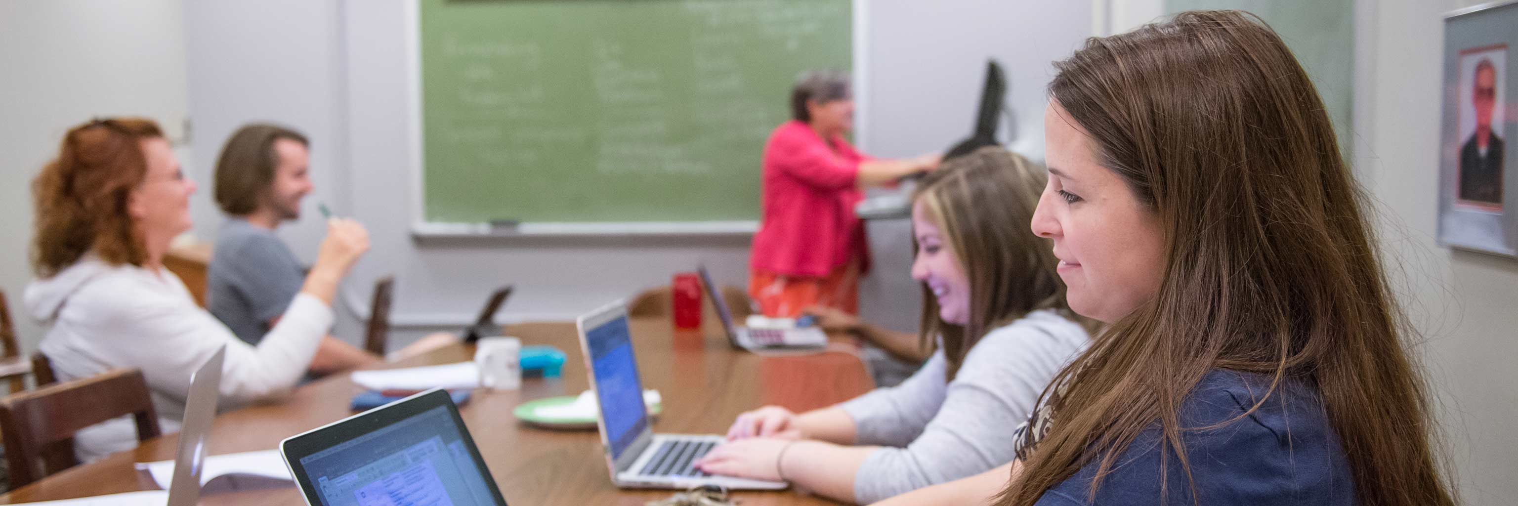 students sitting at a conference table with laptops