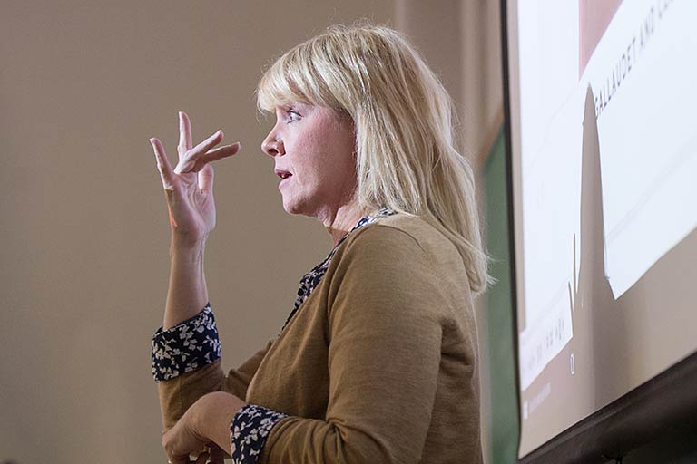 Woman using sign language with projection screen behind her