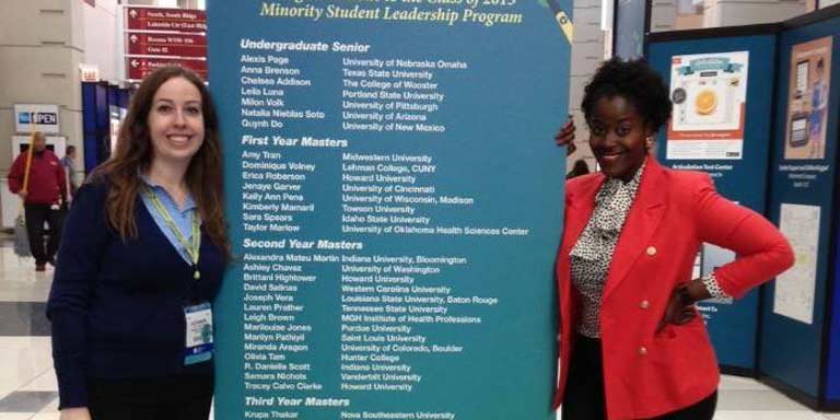 two students stand in front of research banner