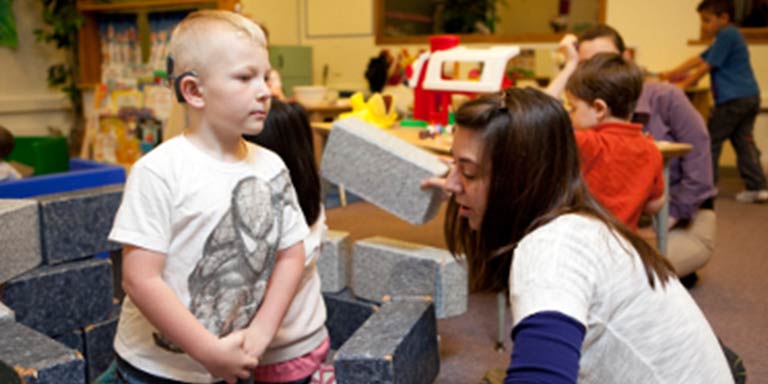 preschool child standing looking at student instructor